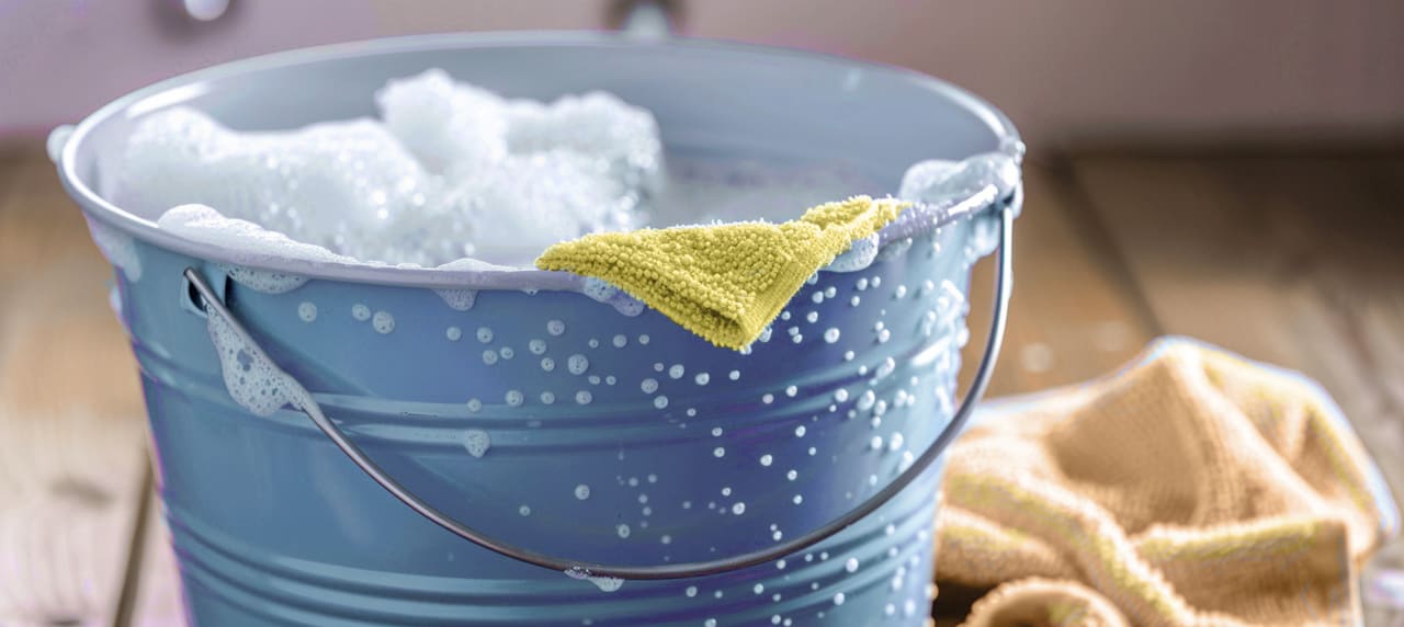 soapy water in a metal bucket with a yellow rag